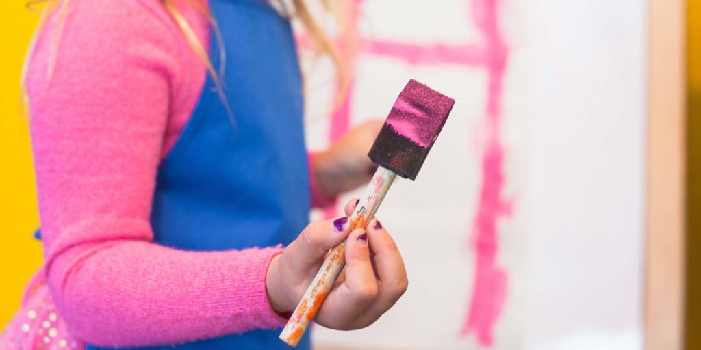 image of a child holding a paint covered brush