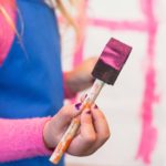 image of a child holding a paint covered brush